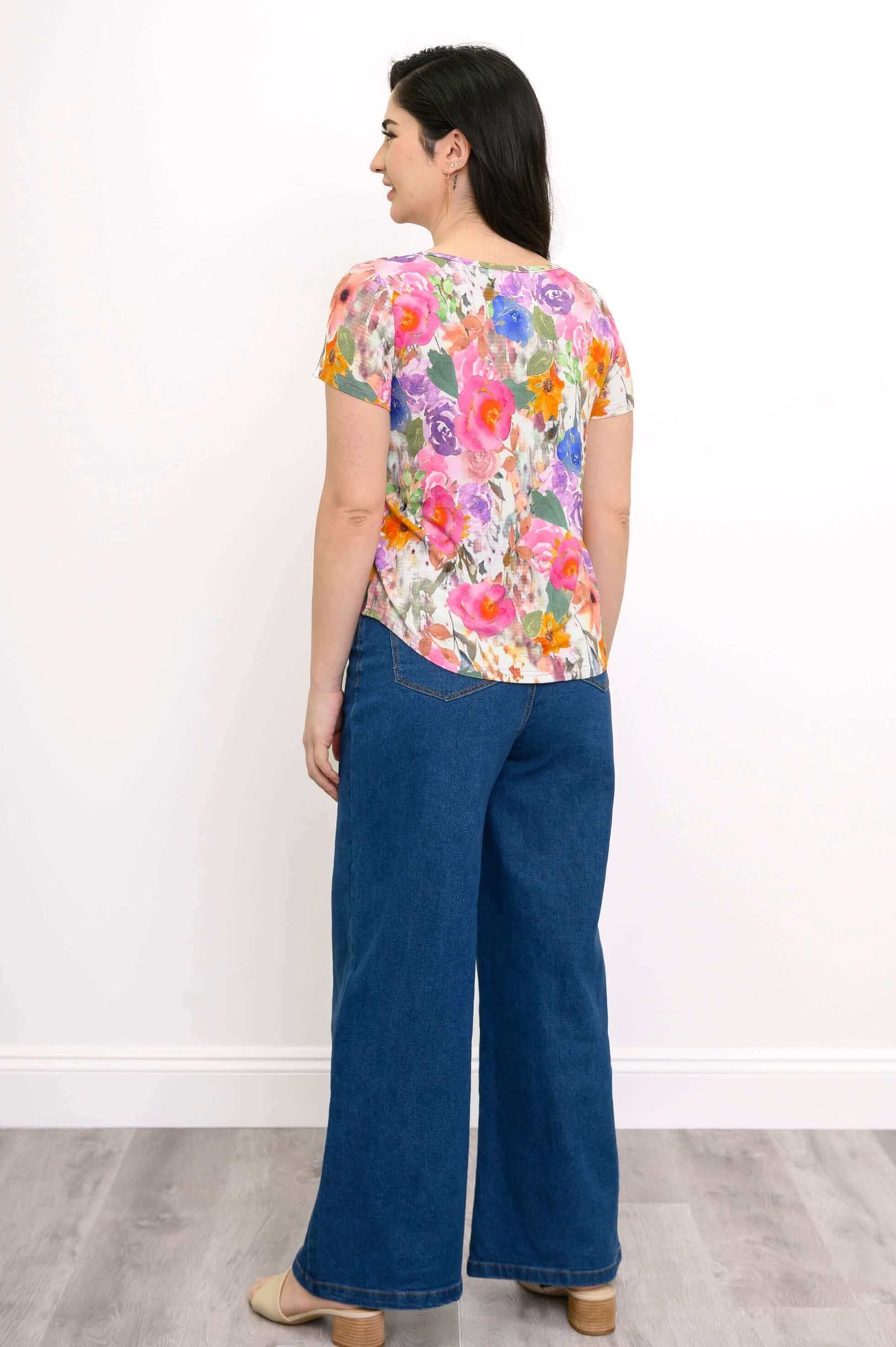 Back view of woman wearing floral print short sleeve top and wide-leg jeans