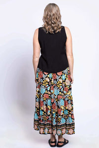 Back view of a woman wearing a sleeveless black top and floral tiered maxi skirt