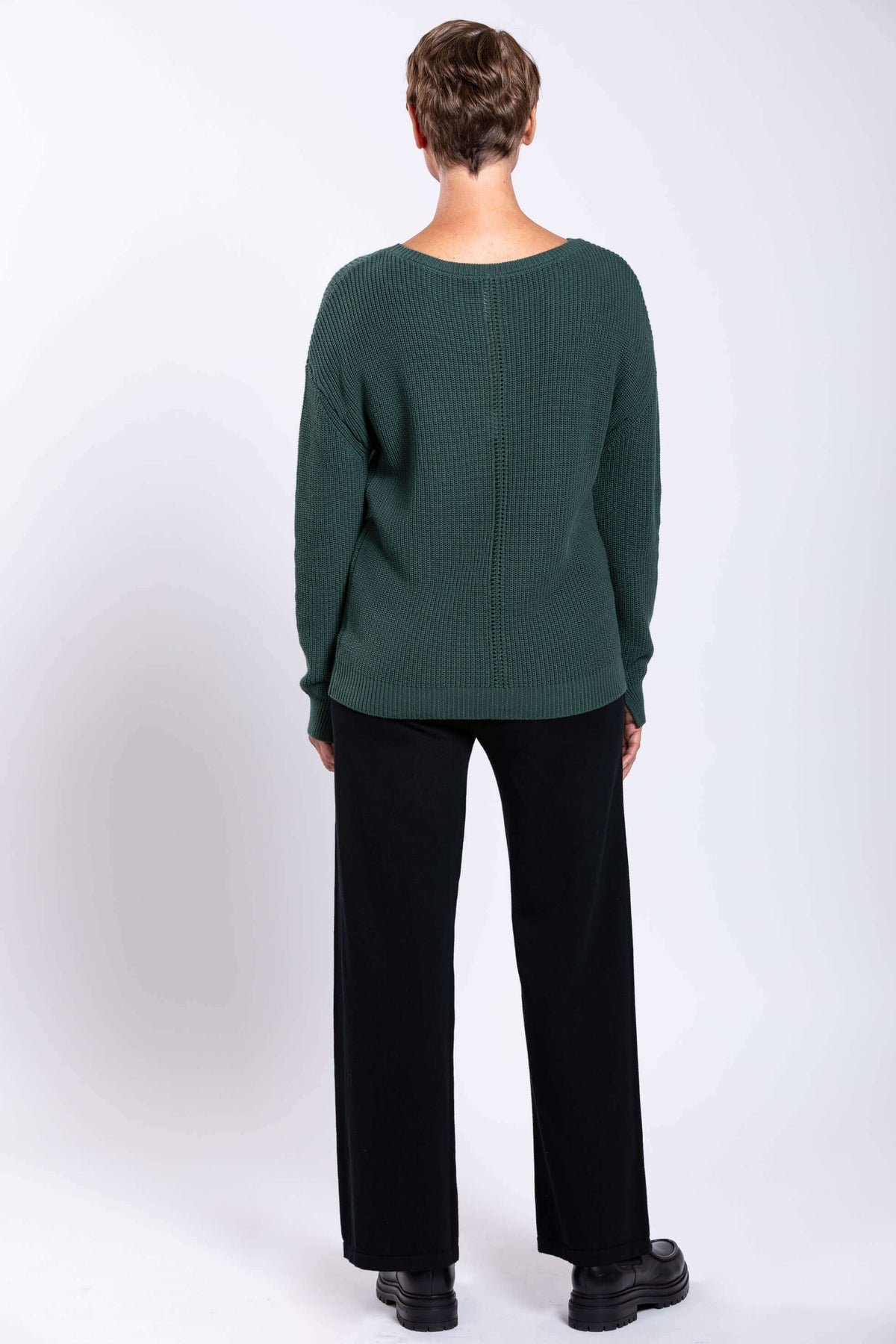 Back view of forest green shaker stitch sweater on woman