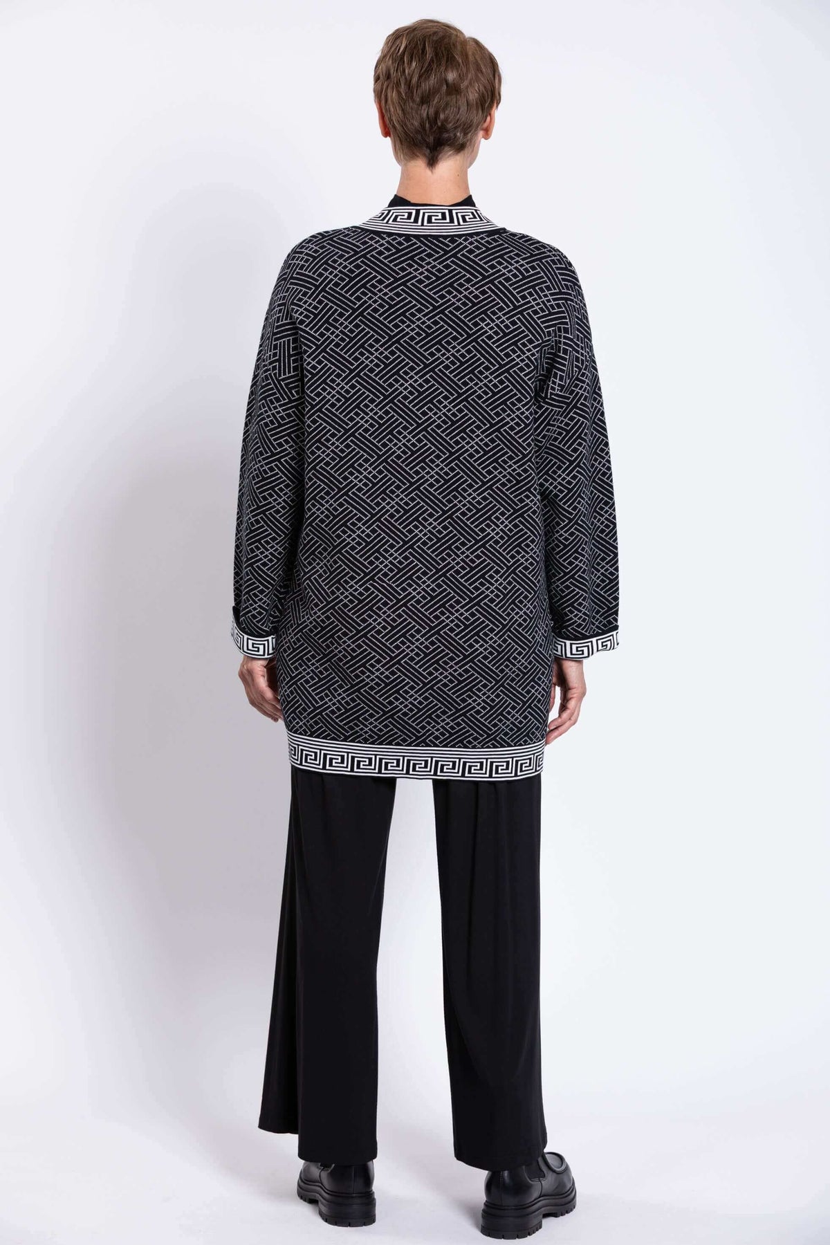 Back view of a model wearing a black and white geometric cardigan with bold trim