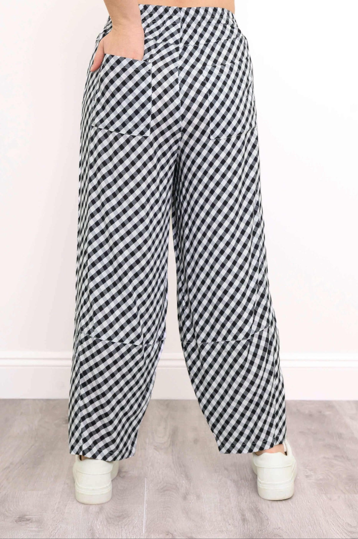 Back view of black and white gingham pants showing patch pockets and white sneakers