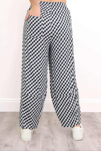 Back view of black and white gingham pants showing patch pockets and white sneakers