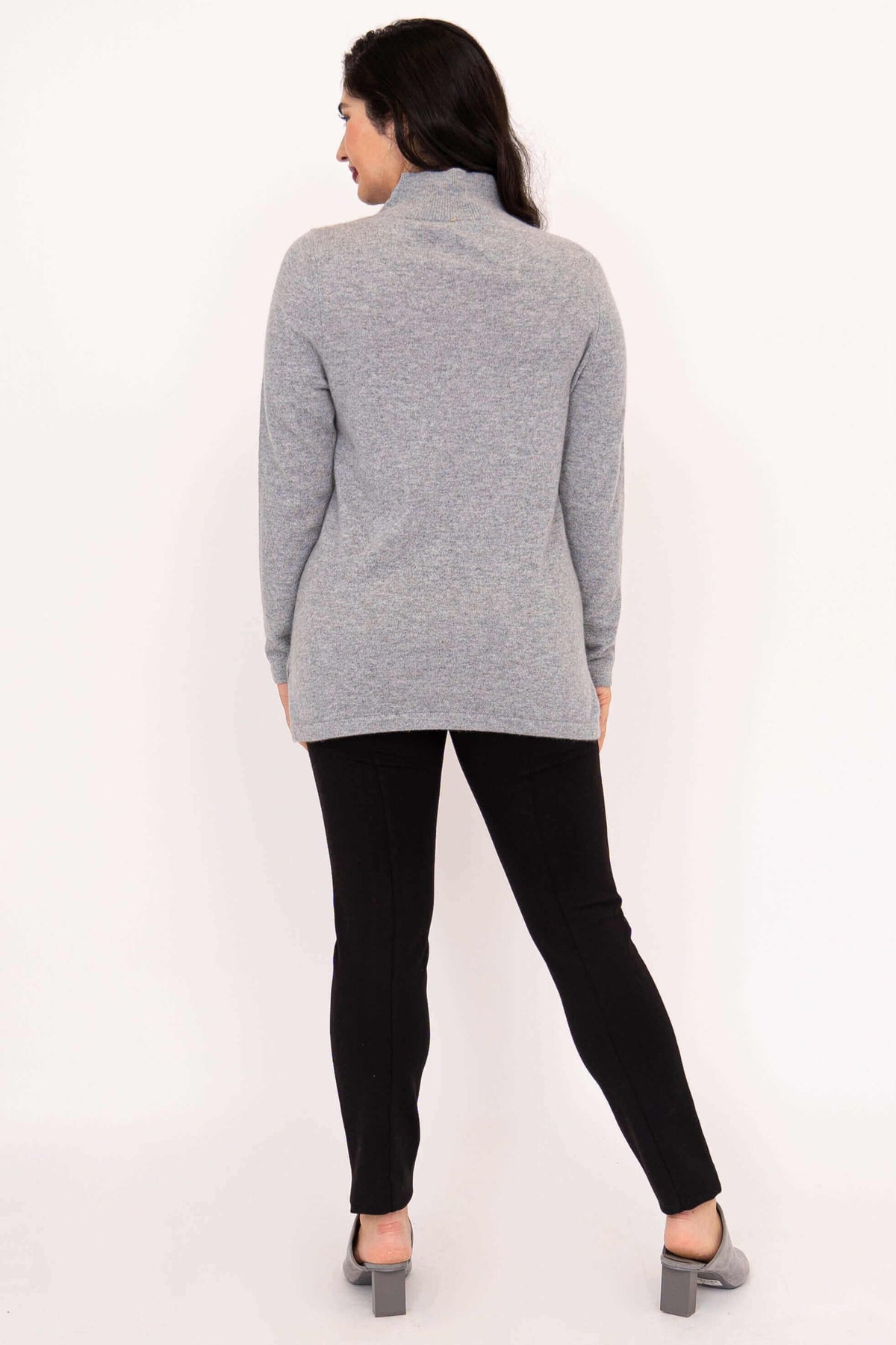 Back view of woman in grey half-zip sweater and black pants