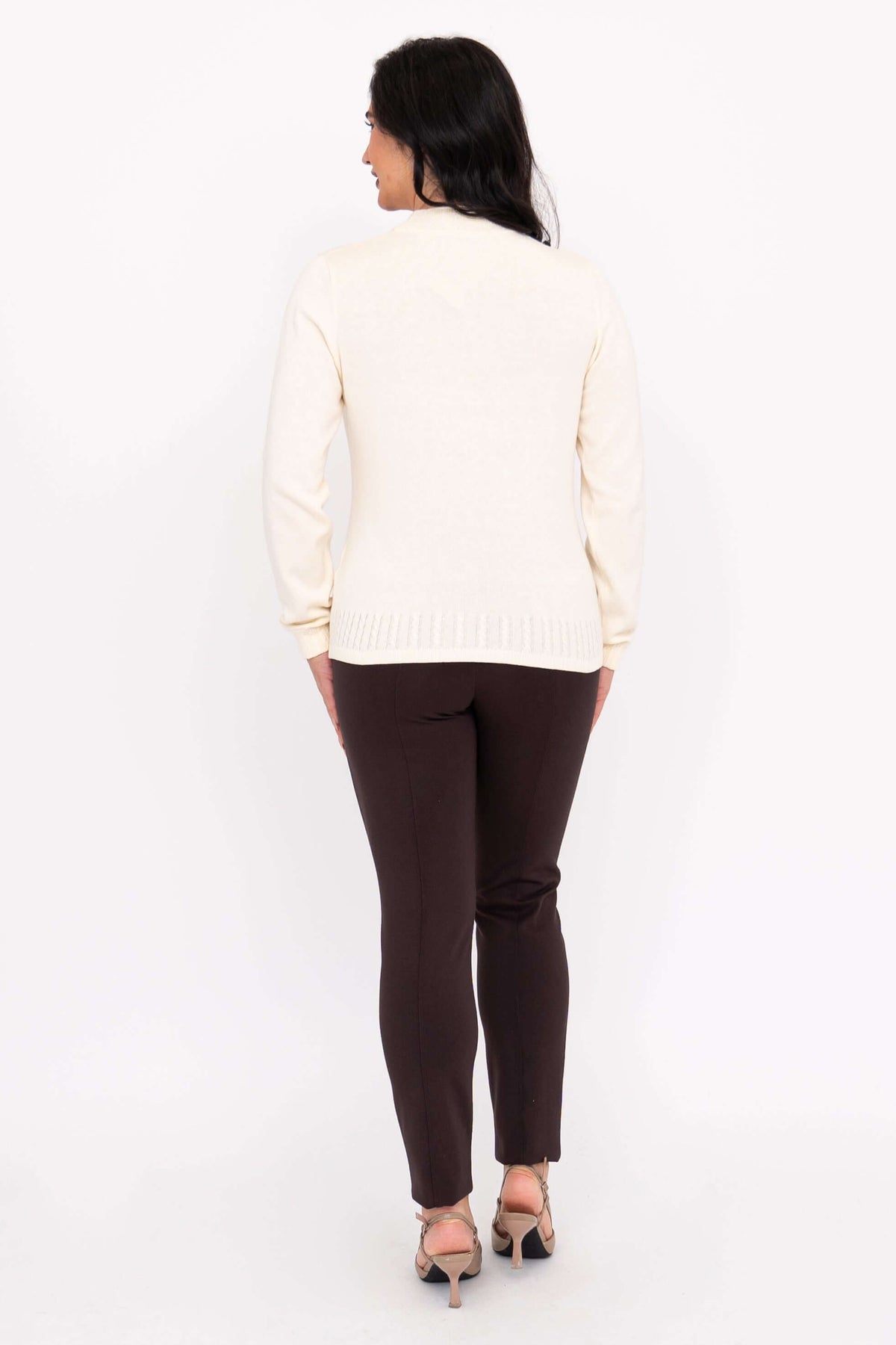Back view of a woman wearing a cream cotton mock neck sweater showing ribbed hem construction.