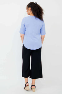 Back view of model in light blue blouse and black wide-leg pants