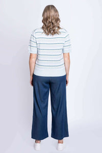 Back view of woman in light blue patterned sweater and wide-leg jeans