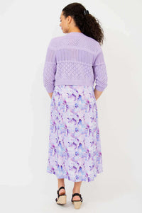 Back view of model in lilac pointelle knit cropped cardigan and watercolor print dress