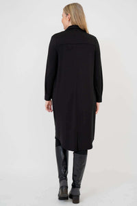 Back view of woman wearing long black duster with curved hem and long sleeves