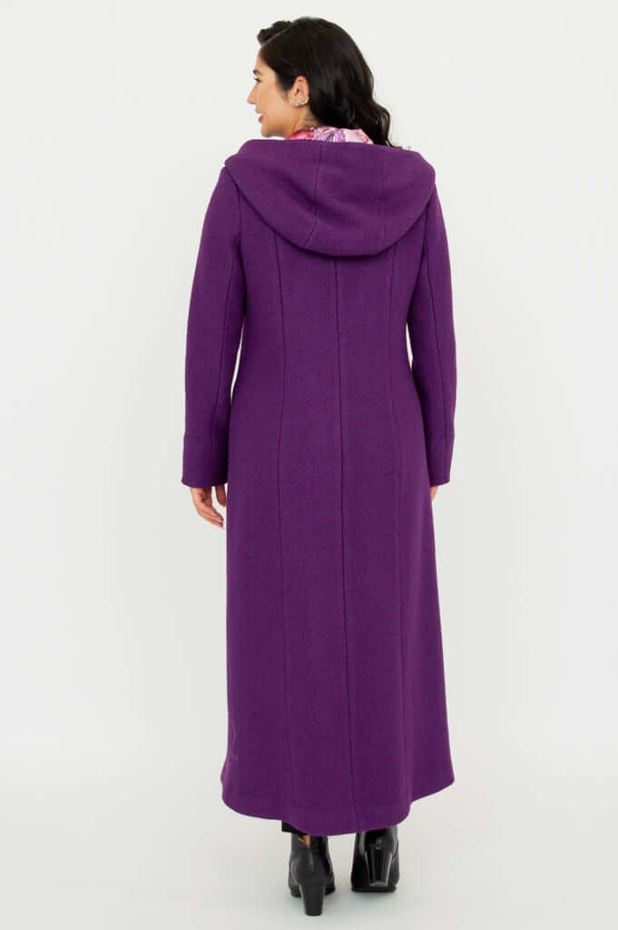 Back view of woman wearing a long purple hooded coat, standing on white background
