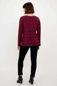 Back view of a magenta patterned long sleeve top paired with black pants and boots