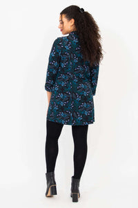Back view of model wearing black, blue, and teal bamboo tunic shirt showing length and fit