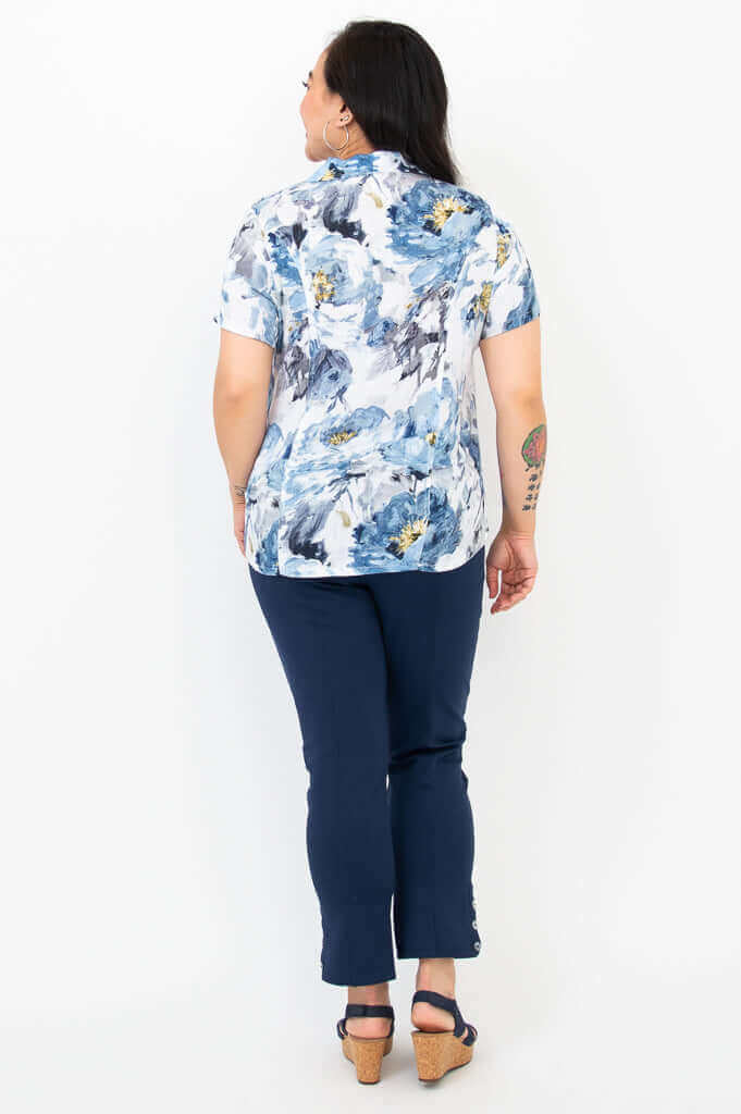 Back view of woman wearing blue and white floral collared shirt with navy pants