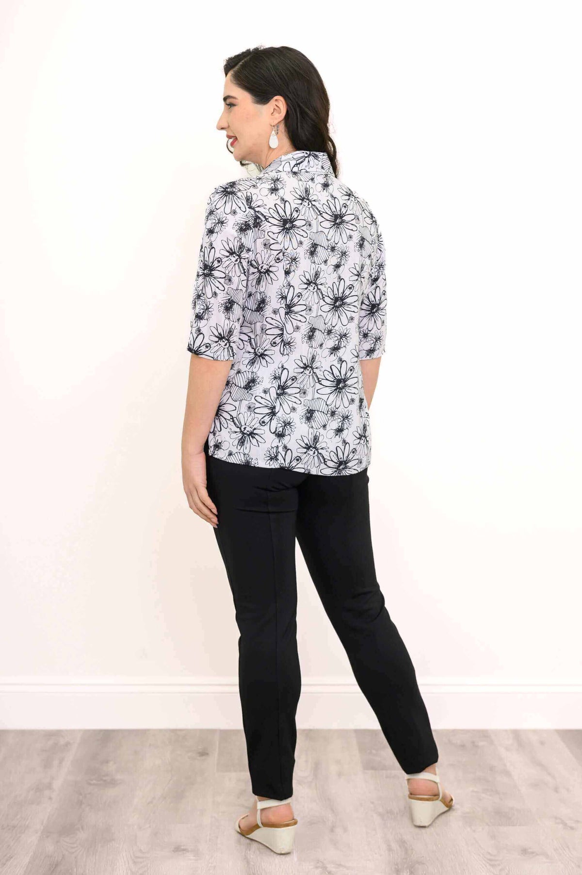 Model facing away, displaying the back of the floral bamboo linen blouse and black pants
