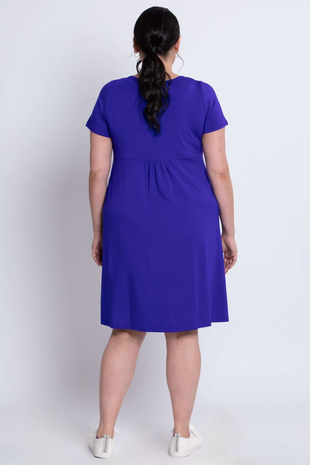 Back view of a model showing the fit of a royal purple dress with short sleeves