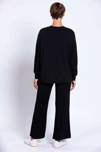 Back view, model showing the rear of black crew neck top and pants