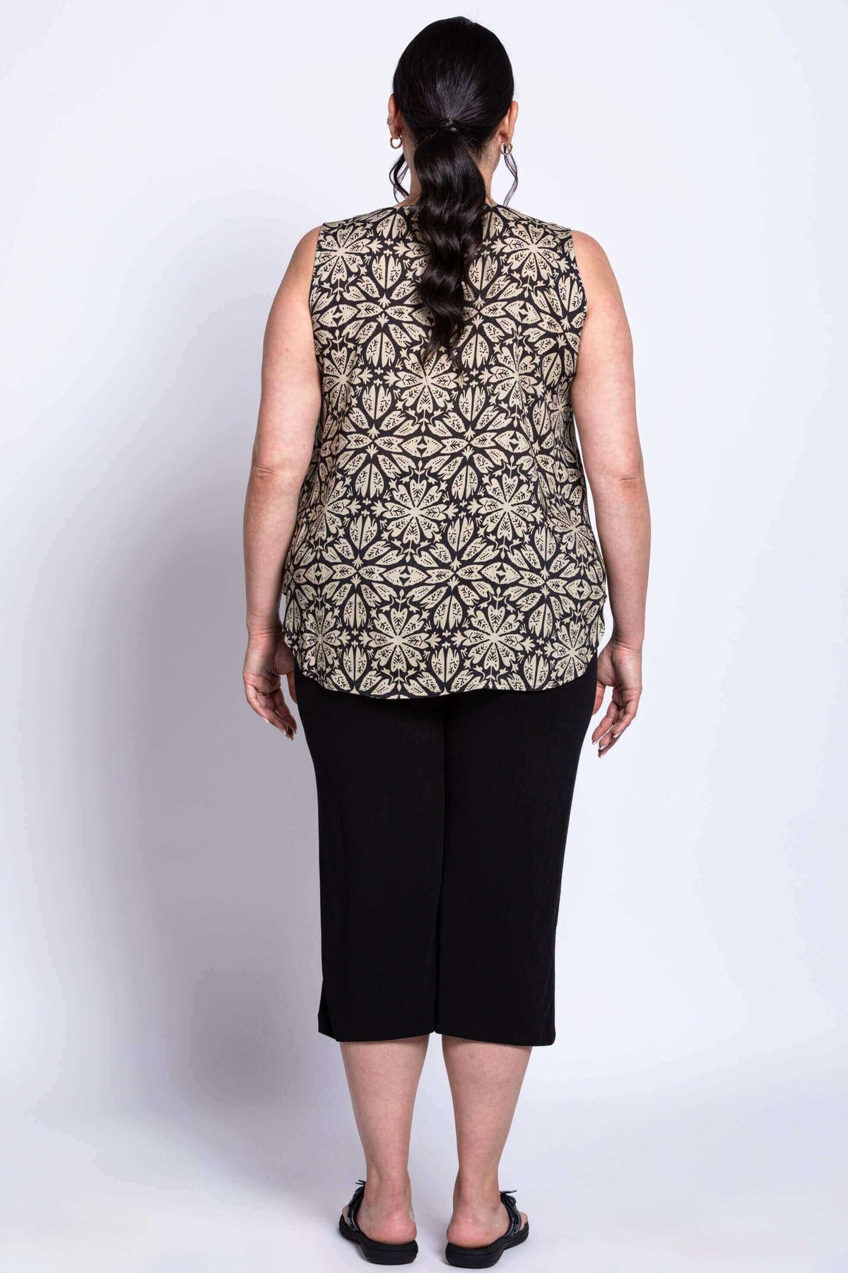 Back view of model wearing black floral sleeveless tank top and black pants