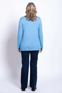 Back view of model wearing light blue sweater and navy pants