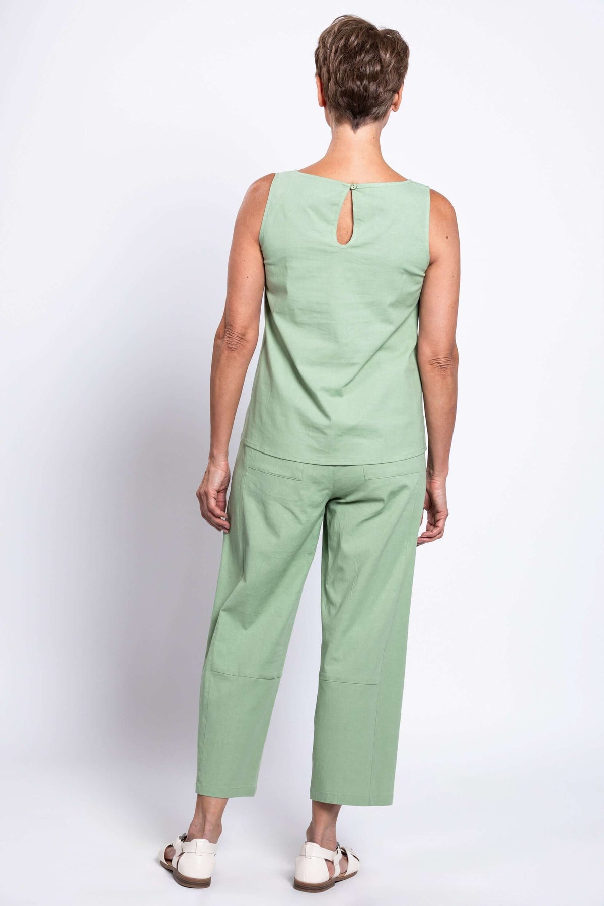 Back view of model wearing sage tank top showing keyhole button closure