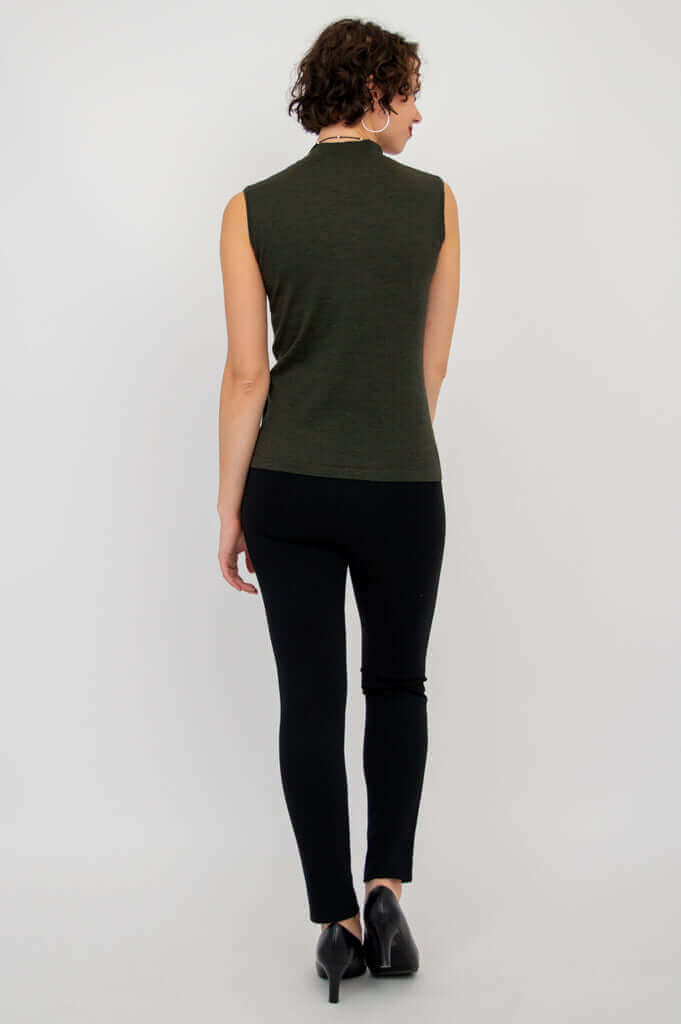 Back view of woman in sleeveless olive-green mock neck sweater and black pants