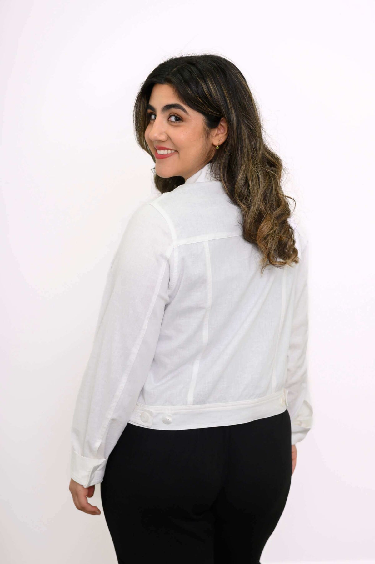 Back view of model wearing white linen-blend jacket highlighting buttoned hem