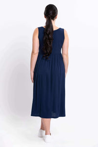Back view of woman wearing sleeveless navy empire waist midi dress and white sneakers