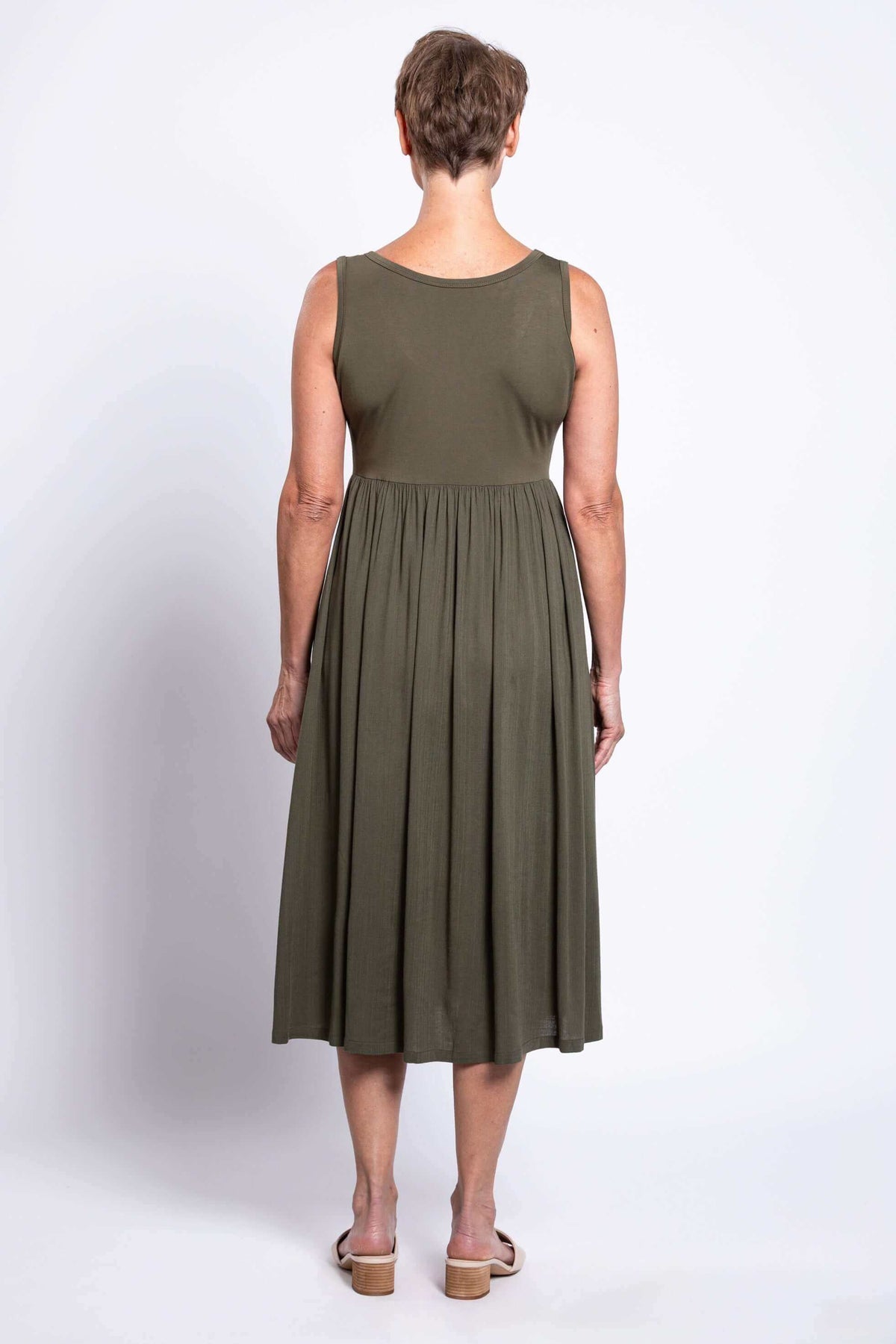 Back view of woman in olive empire waist midi dress with short hair