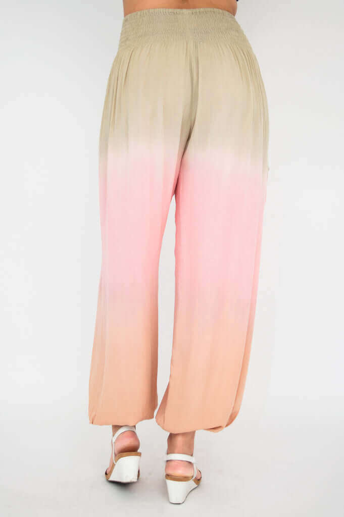 Back view of ombre boho pants, elastic waistband and flowing peach-pink gradient fabric