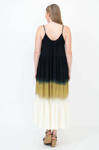 Back view of woman in a sleeveless black to golden ombre maxi dress with adjustable straps