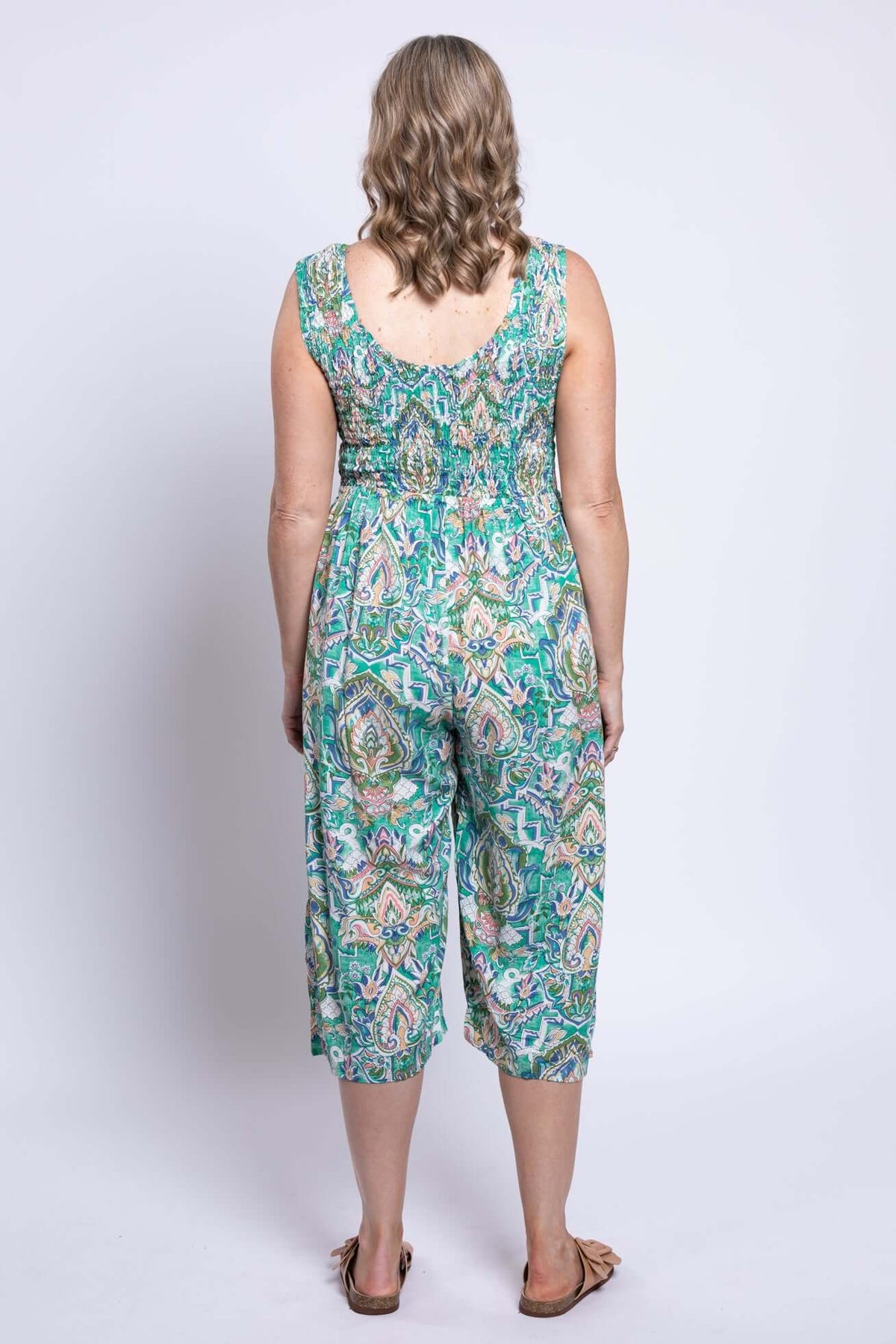 Back view of a woman in a green paisley jumpsuit with elasticized bodice and flowy cropped legs