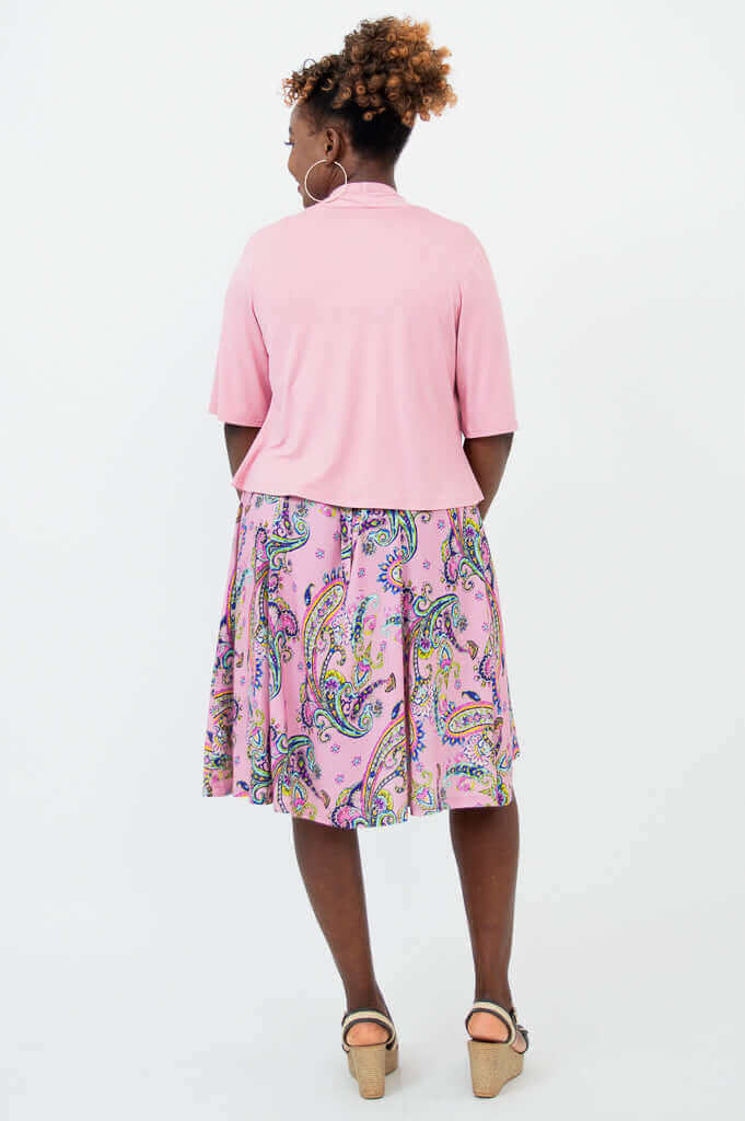 Back view of woman wearing a light pink cropped jacket and pink paisley dress