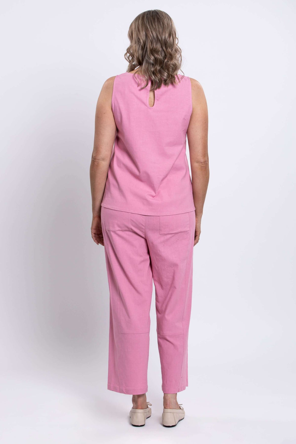 Woman in pink tank top and pants, back view showing button closure detail