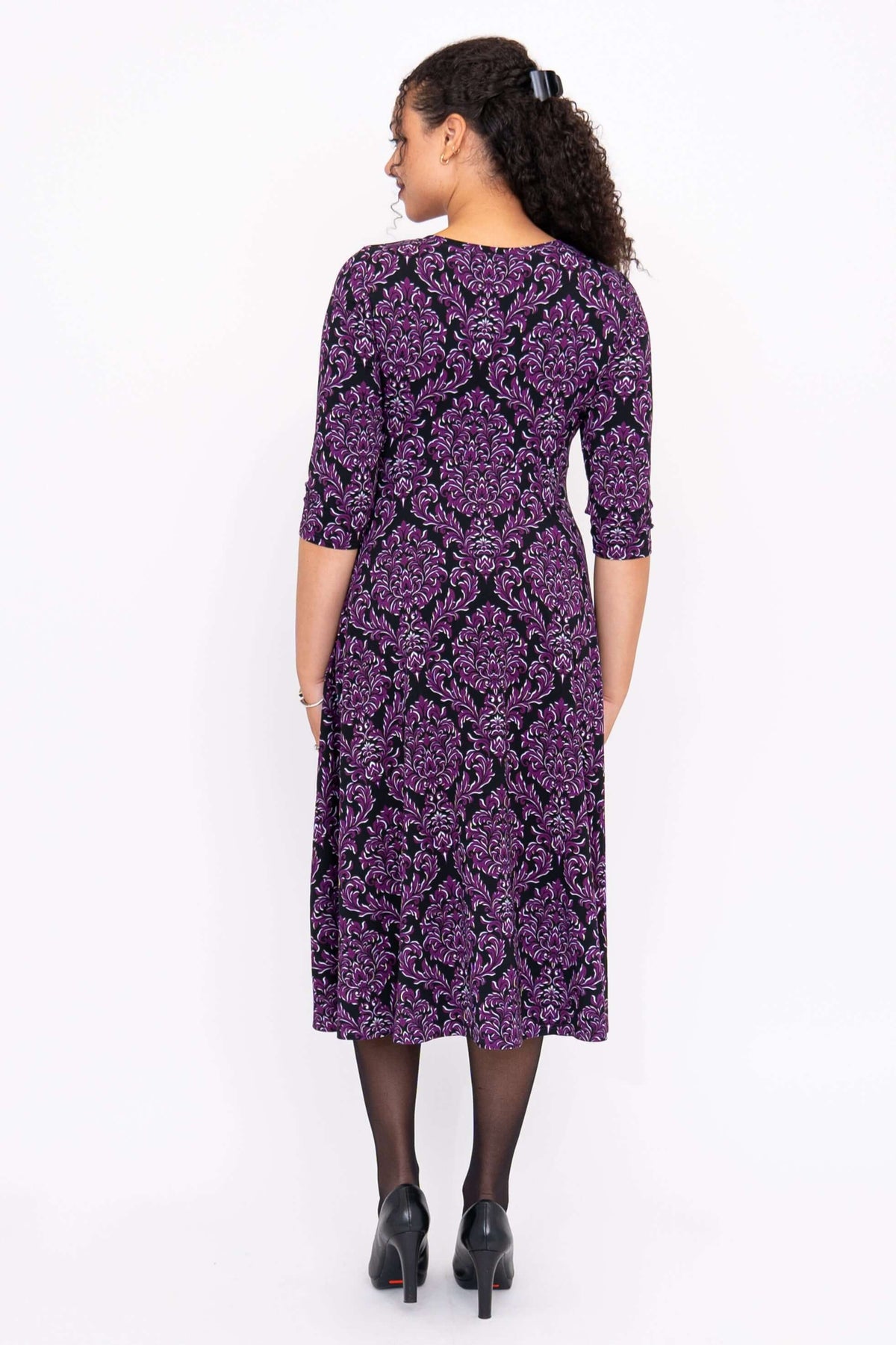 Back view of model wearing a purple damask midi dress with an A-line skirt