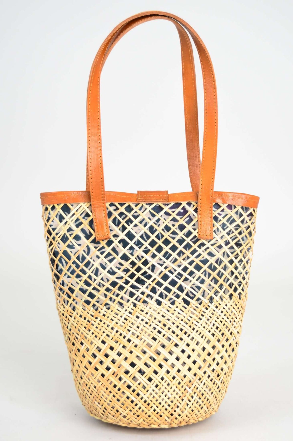 Back view of rattan basket tote with blue printed lining and leather handles