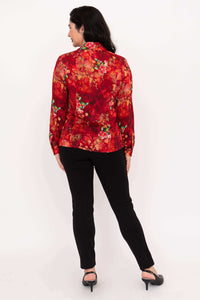 Back view of woman wearing a red floral blouse with long sleeves and black pants