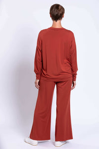 Rear view of woman in rust relaxed fit bamboo crew neck top and wide-leg pants