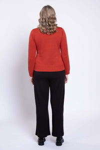 Back view of a woman wearing a rust red cotton sweater with cable knit accents