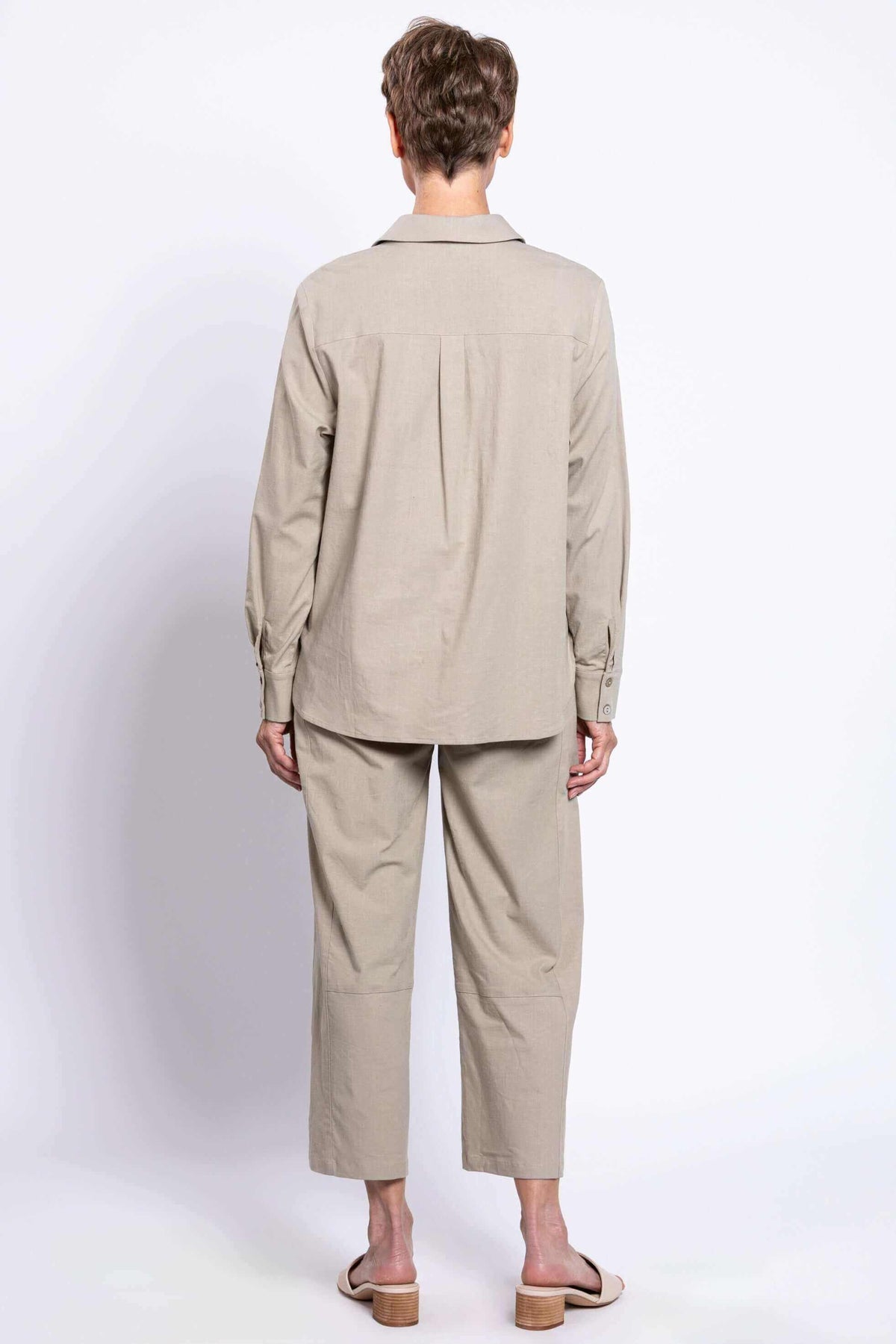 Back view of woman wearing sage relaxed linen shirt and matching pants