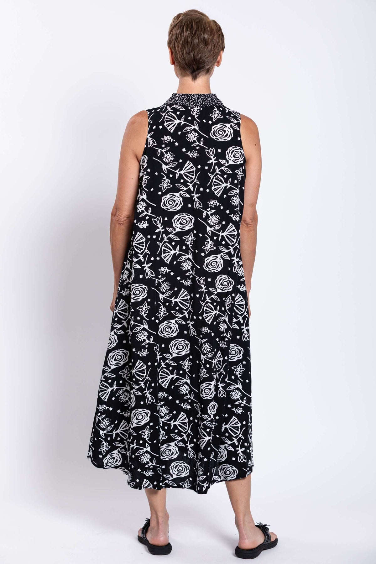 Rear view showing the back of a sleeveless black dress with white abstract floral designs