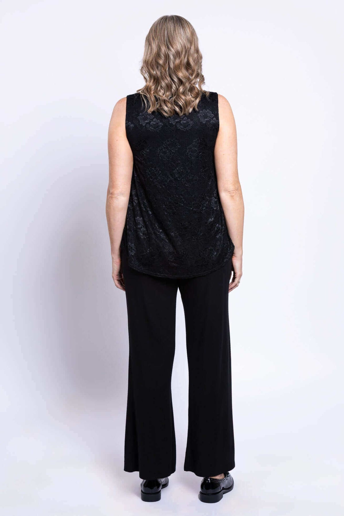 Back view of woman in sleeveless black lace tank top and black pants