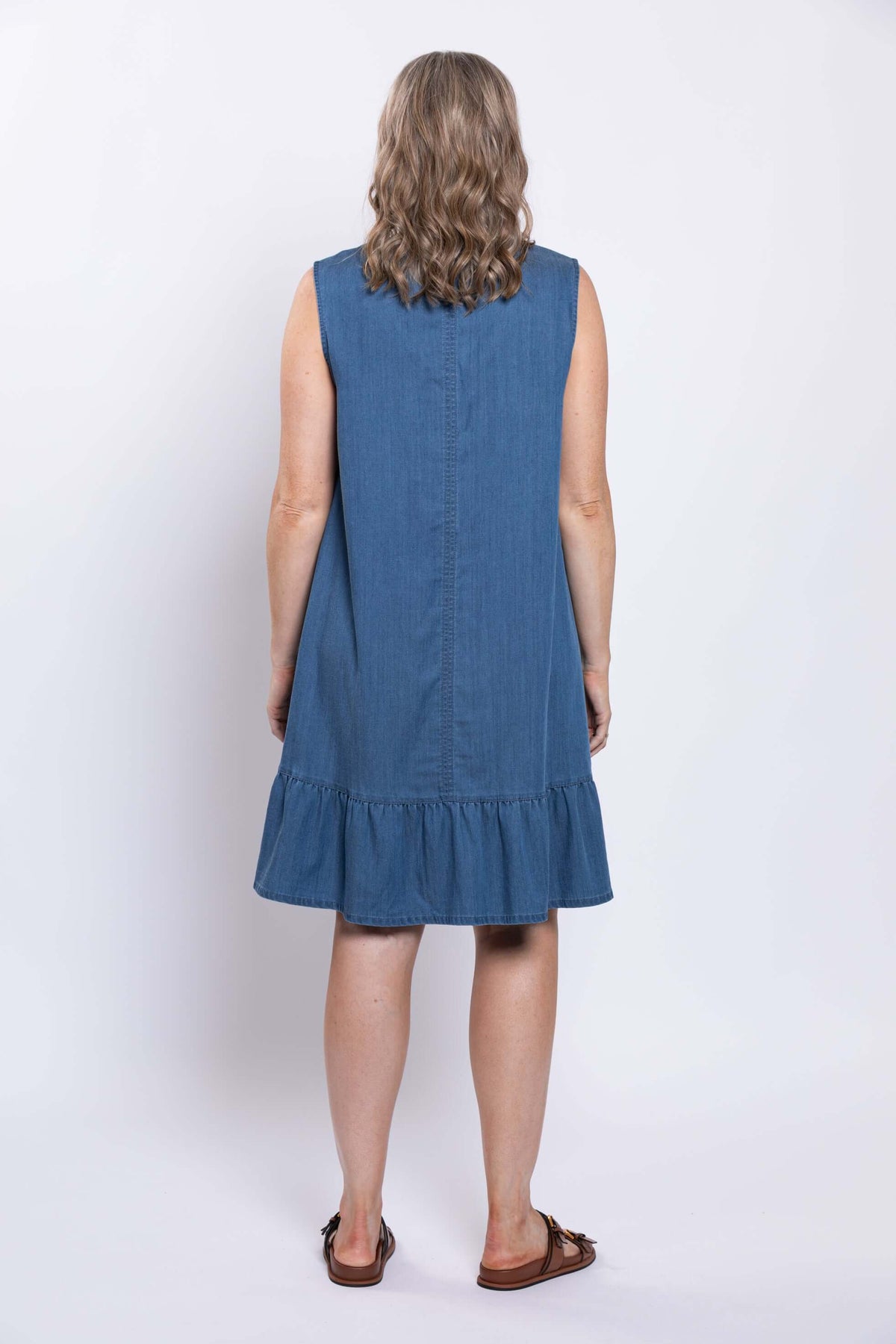 Back view of a woman wearing a sleeveless blue dress with ruffle hem