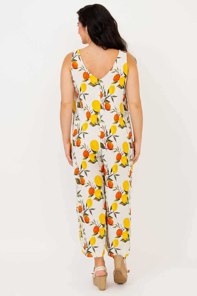 Woman wearing sleeveless jumpsuit with citrus fruit print, back view