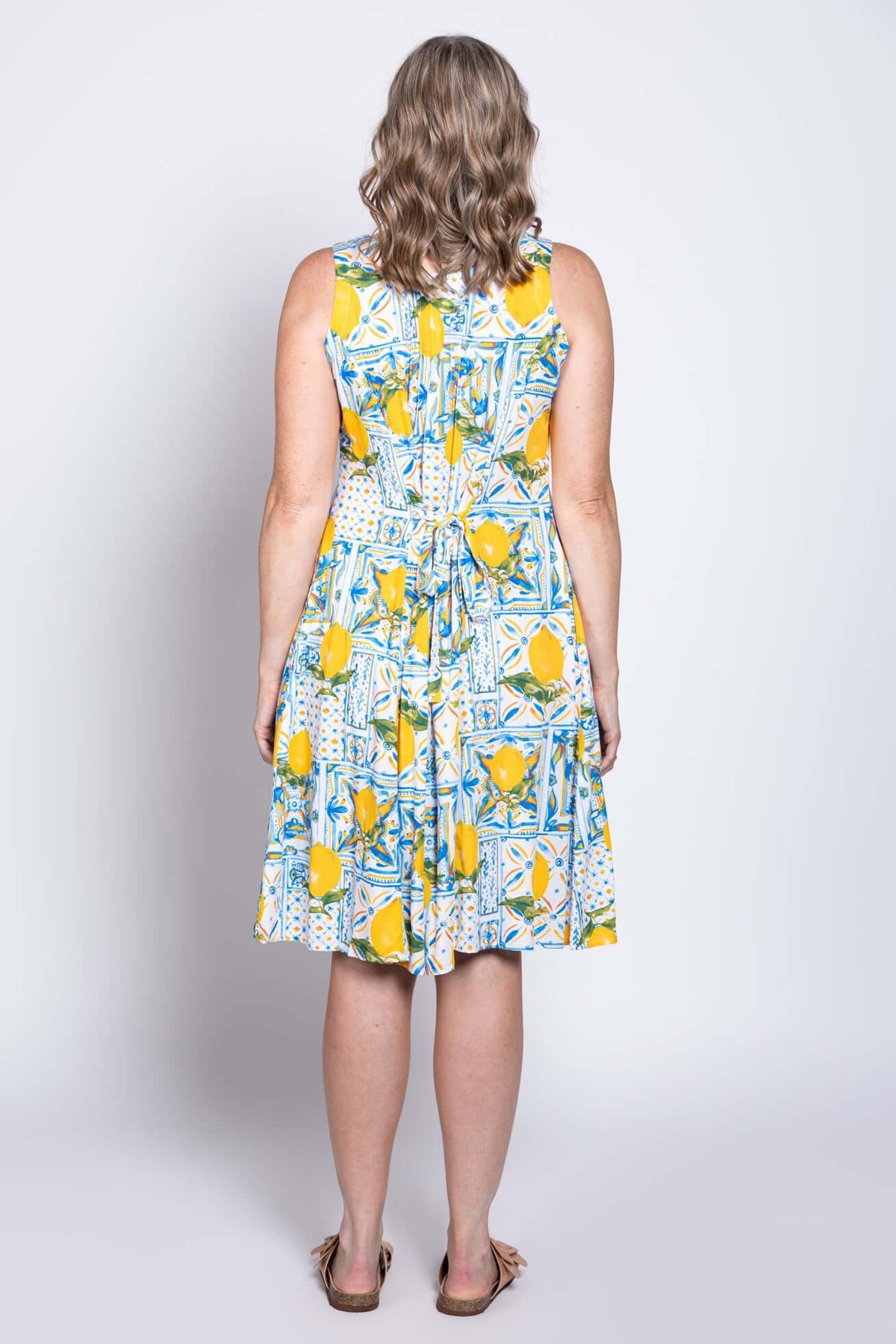 Back view of woman wearing a sleeveless dress with tie-back and lemon print