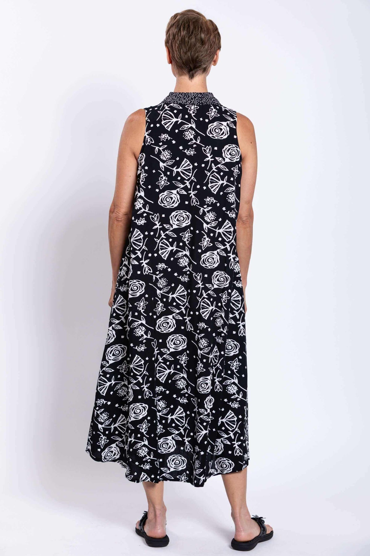 Back view of woman in black sleeveless dress with white print