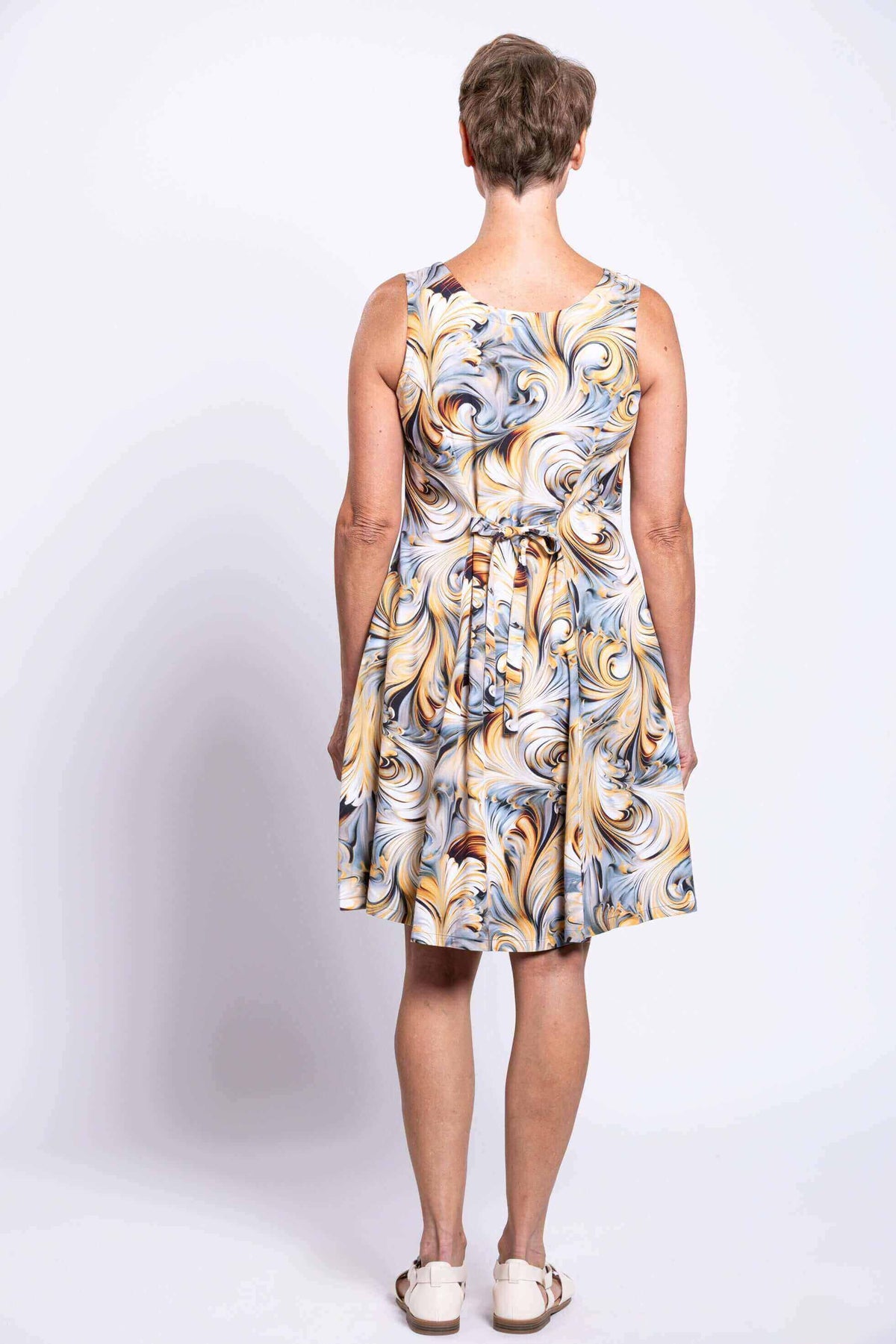 Back view of swirl print sleeveless dress showing tie-belt detail