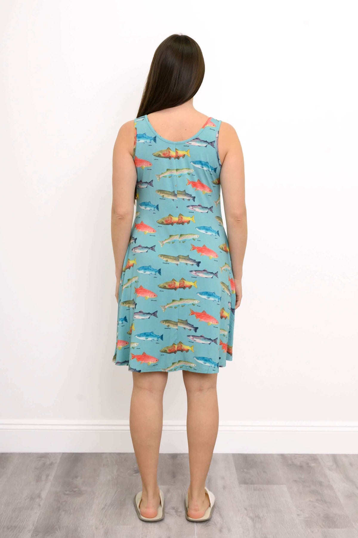 Back view of woman in turquoise sleeveless dress with detailed fish design