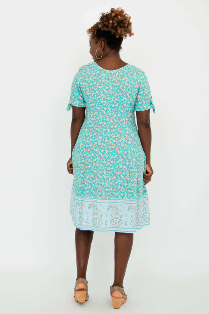 Back view of woman in teal floral midi dress with decorative border