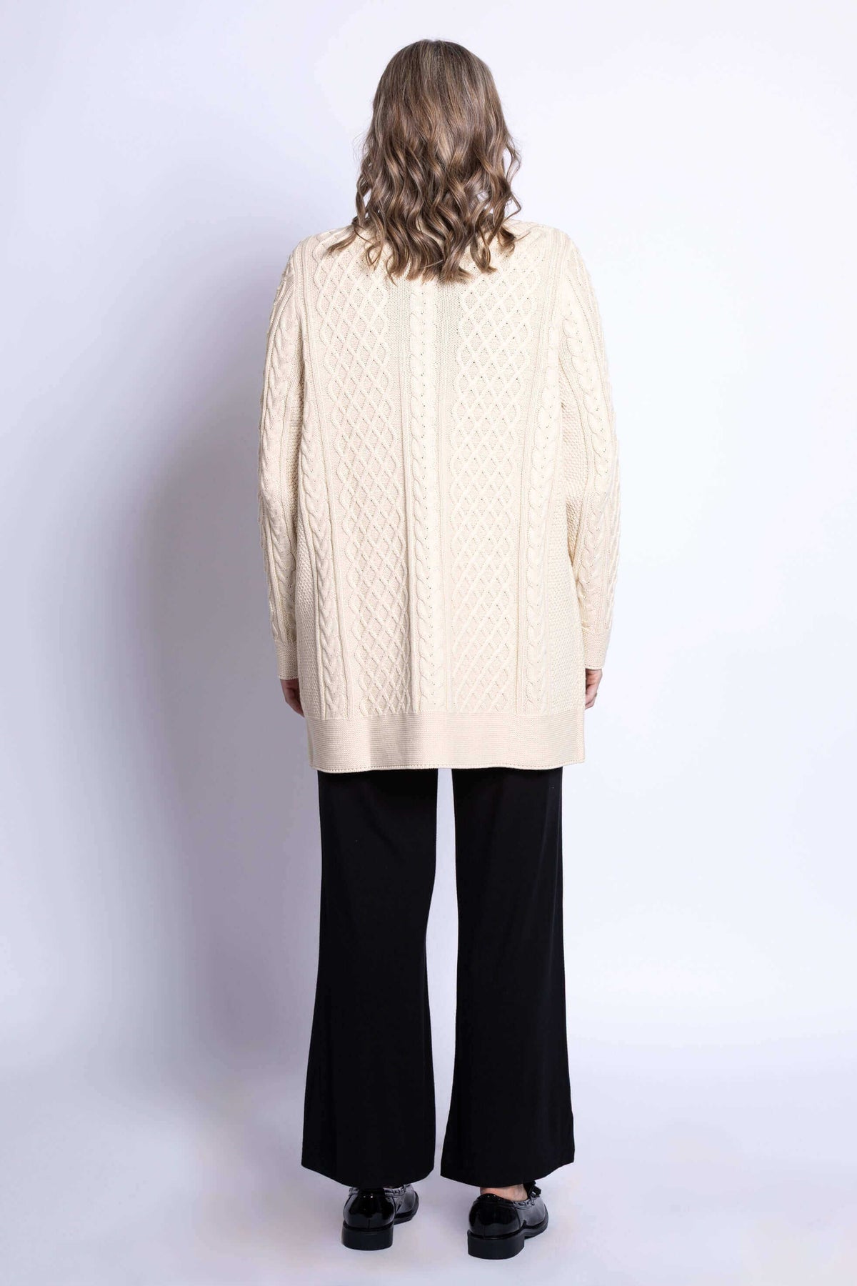 Back view of woman wearing cream cable knit cardigan with textured pattern