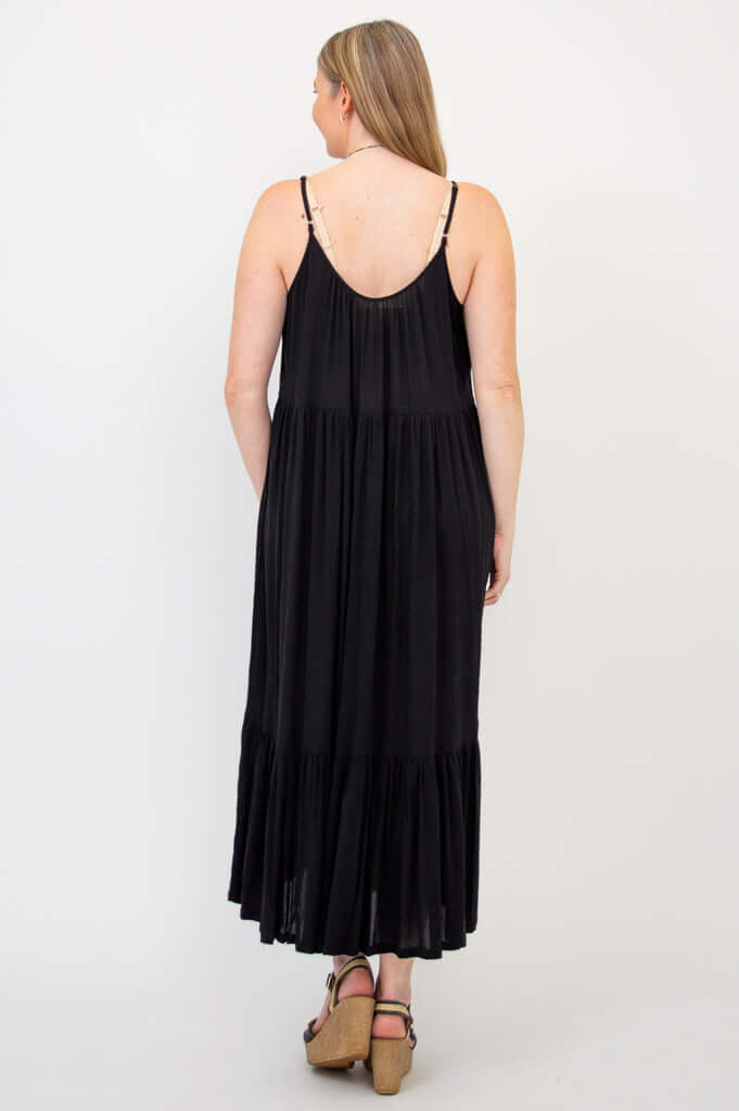 Back view of a woman in a black tiered maxi dress with adjustable straps