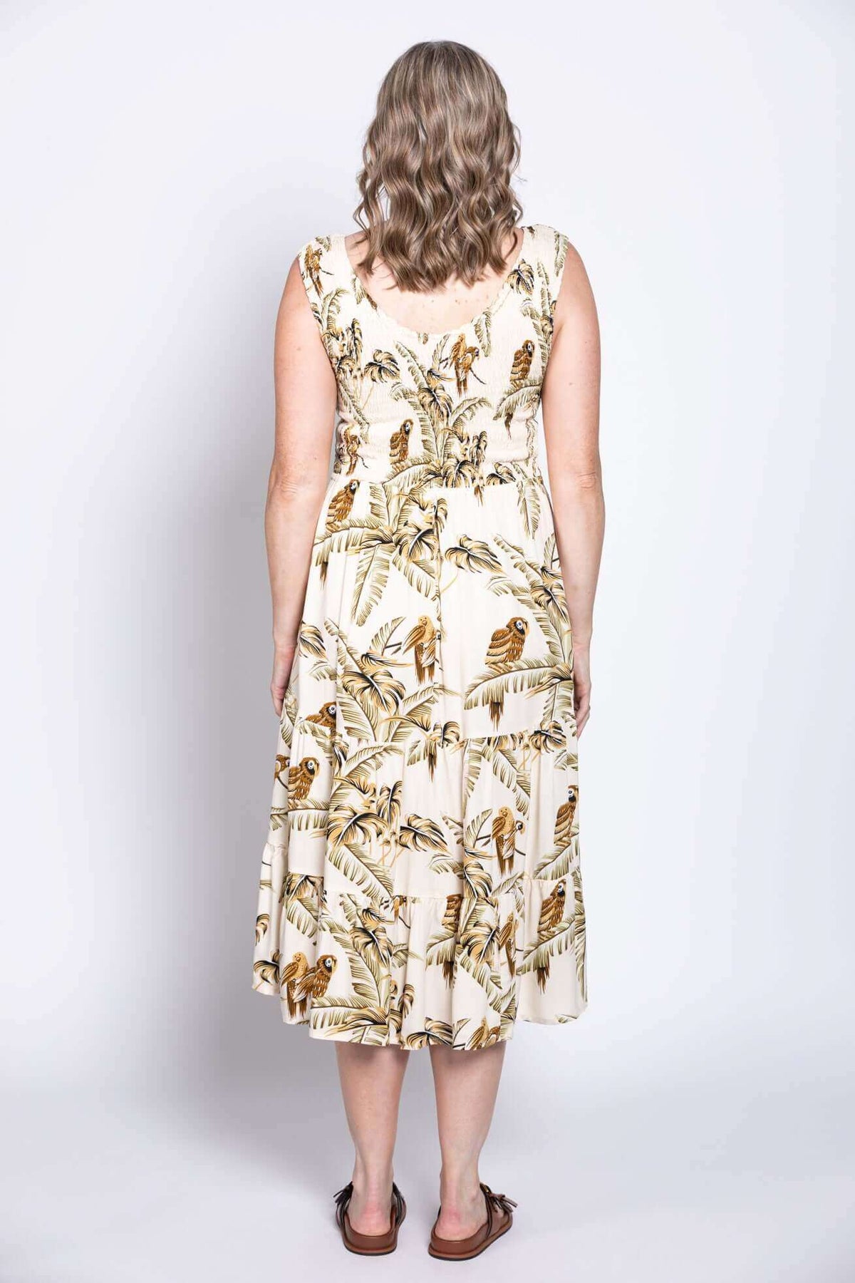 Back view of woman in cream tropical print midi dress