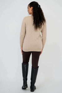 Back view of woman in beige wool cashmere sweater and black boots